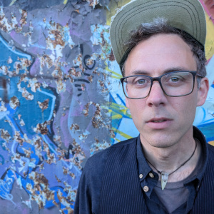Andy Brunner vor einer blauen Wandmalerei.